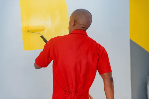 Industrial painter applying paint to wall